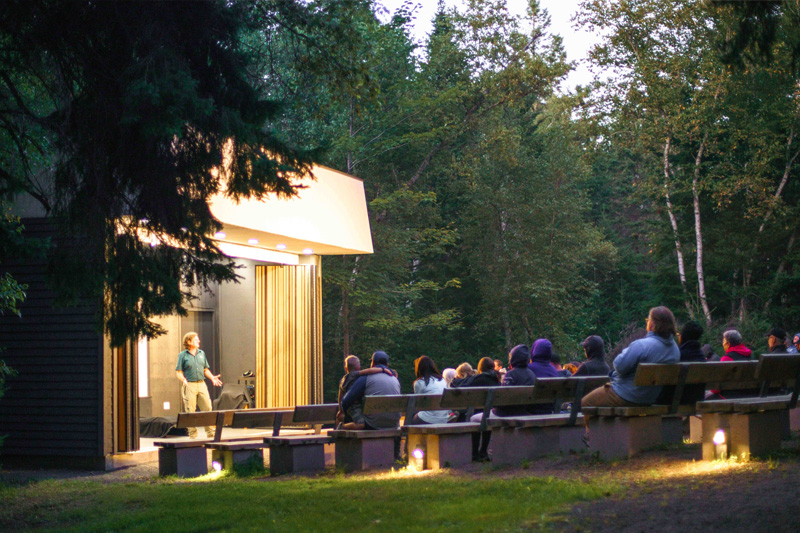 A Parks Canada interpreter talks to an audience at the outdoor theatre