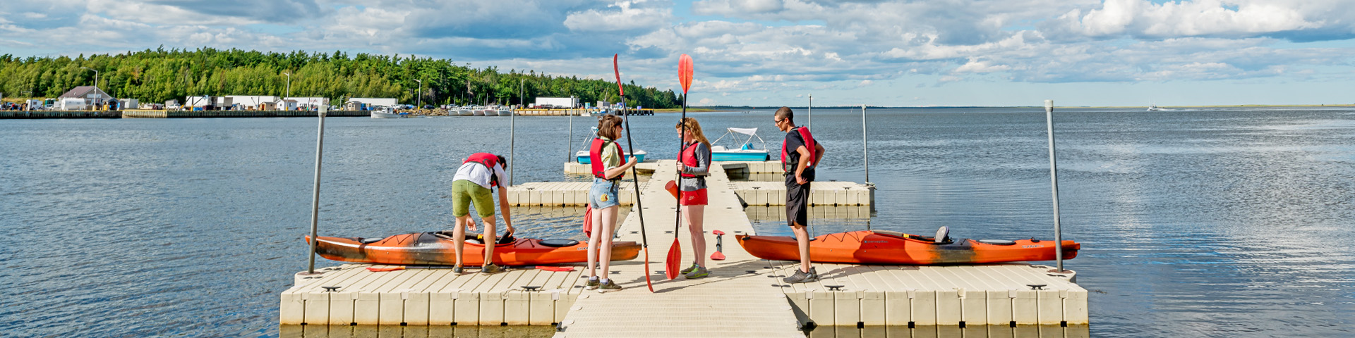 Visitors on a floating dock, with kayaks in the water.