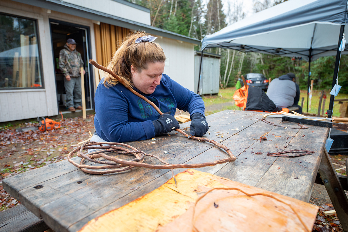 a woman carves a wooden branch