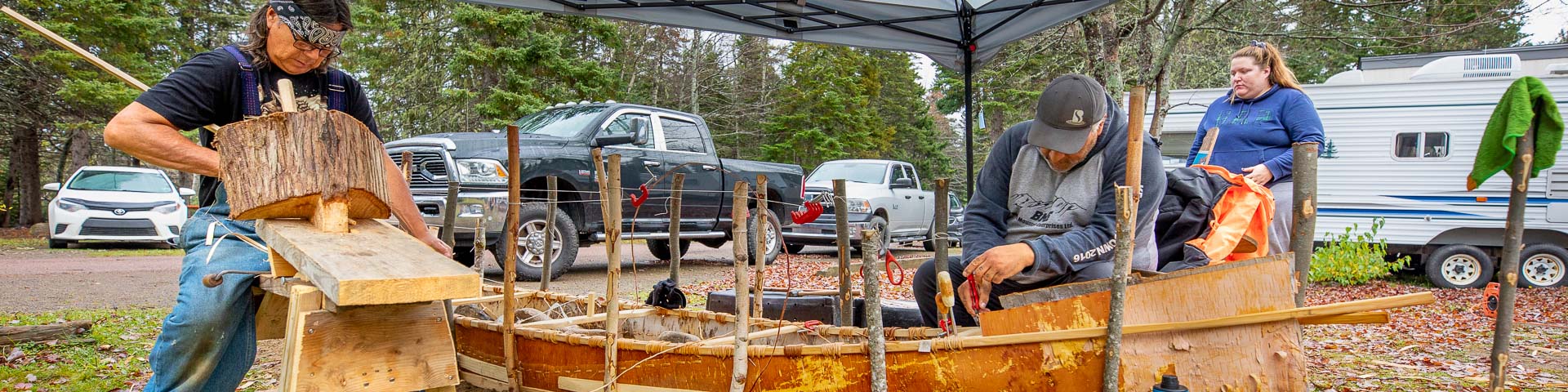 Un groupe d'Autochtones fabriquant un canot en écorce de bouleau dans le terrain de camping du parc national Kouchibouguac.