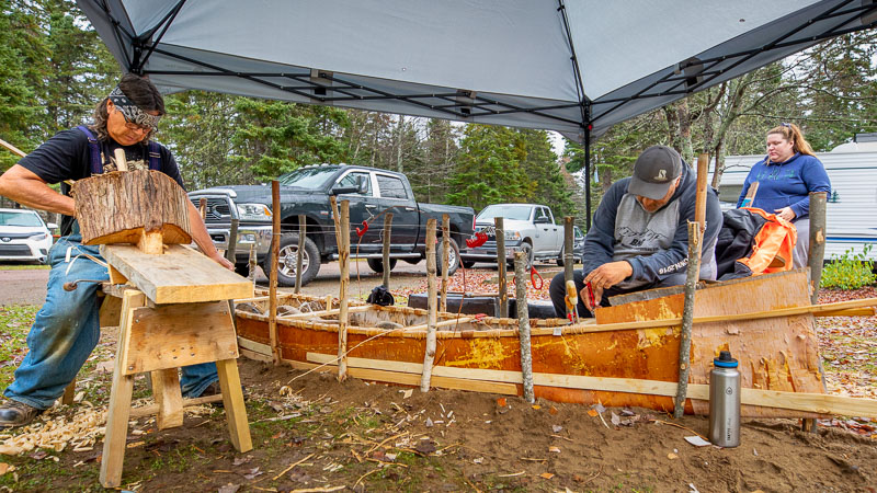 Des autochtones construisent un canot en écorce de bouleau au terrain de camping.