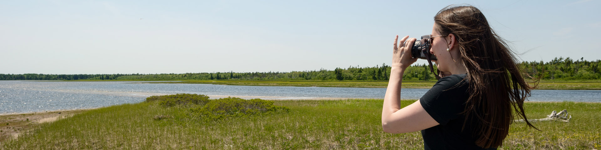 Une visiteuse avec une caméra prends en photo la lagune.