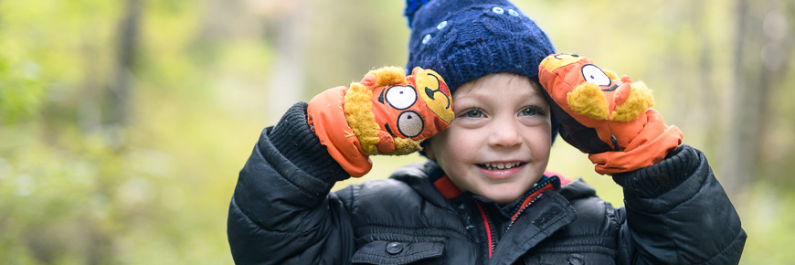 A kid touching his face with his mittens