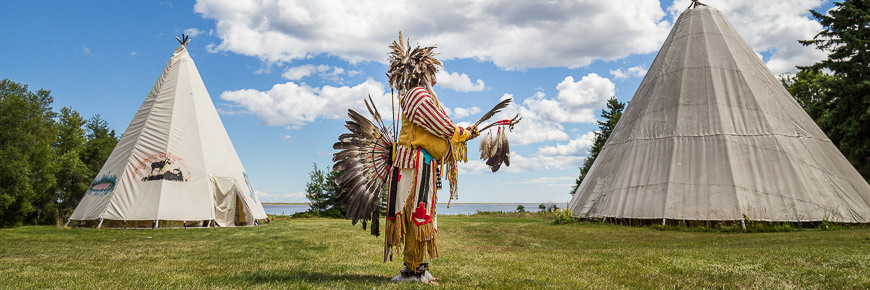 A Mi'gmaq elder between two wigwam