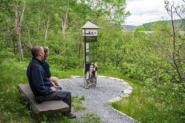 Two people taking a break on a bench at the Mattie Mitchell hiking trail in Gros Morne National Park