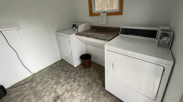 A room with two dryers, a small counter, and a window