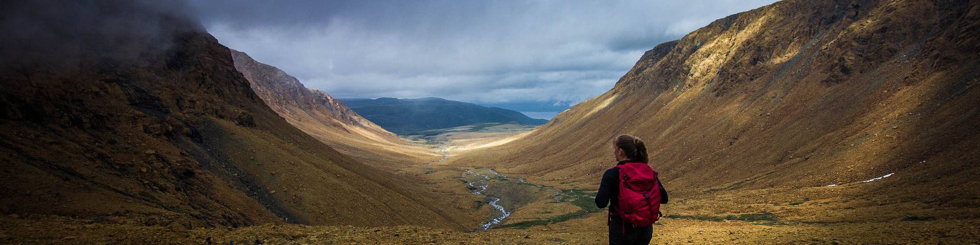 A hiker stands in a rocky valley in the Tablelands of Gros Morne National Park