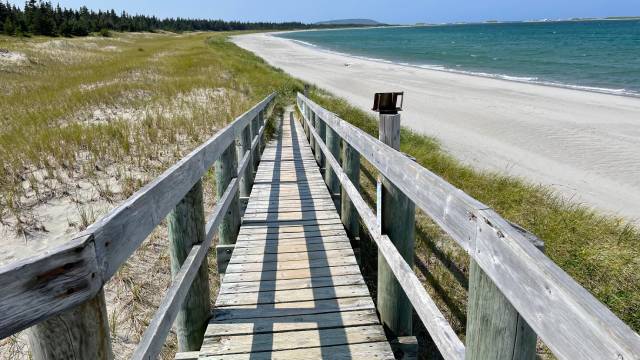 A wooden ramp leading to a sandy beach.
