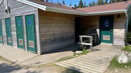 A boardwalk leading to wooden building with green doors.