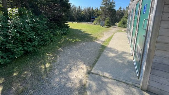 :A gravel path in front of a wooden building with green doors.