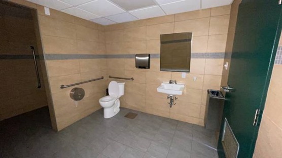 A large bathroom with a toilet, sink, and grab bars