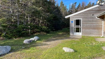 A grassy pathway leading to a wooden building.