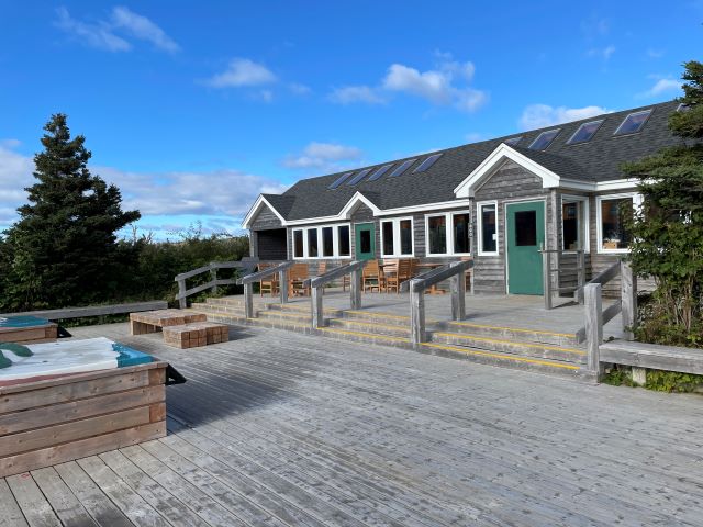 A large wooden deck with leading to stairs and a wooden building. 