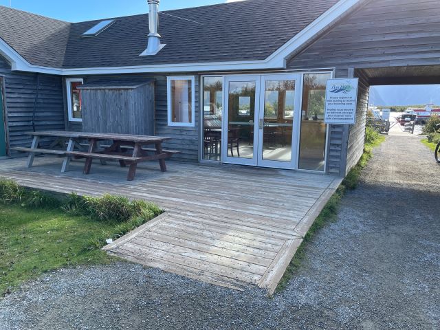 A wooden ramp leading from a gravel path to a wooden building with double doors.