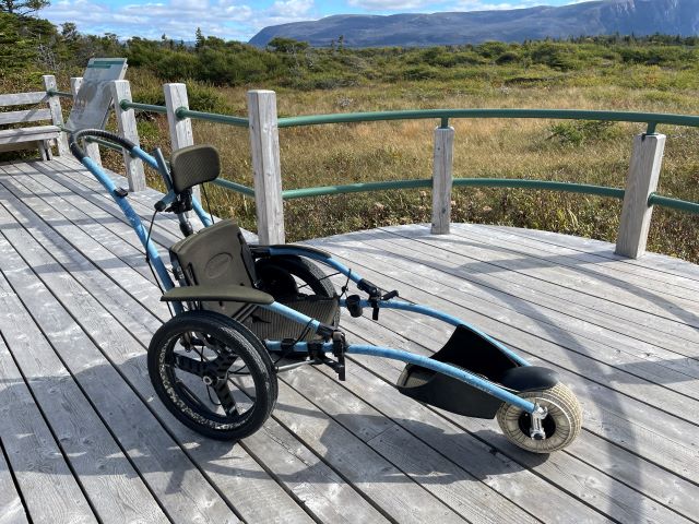 An all-terrain wheelchair on a wooden deck. 