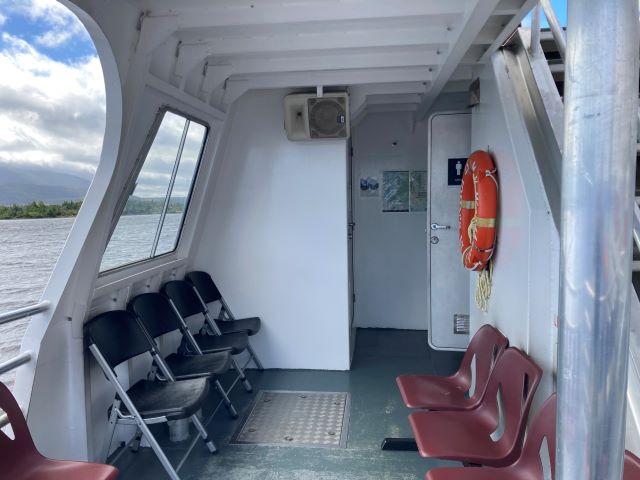 Interior of a tour boat with chairs and windows.