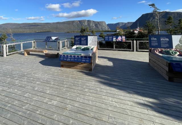 A wooden deck with a body of water and mountains in the background.

