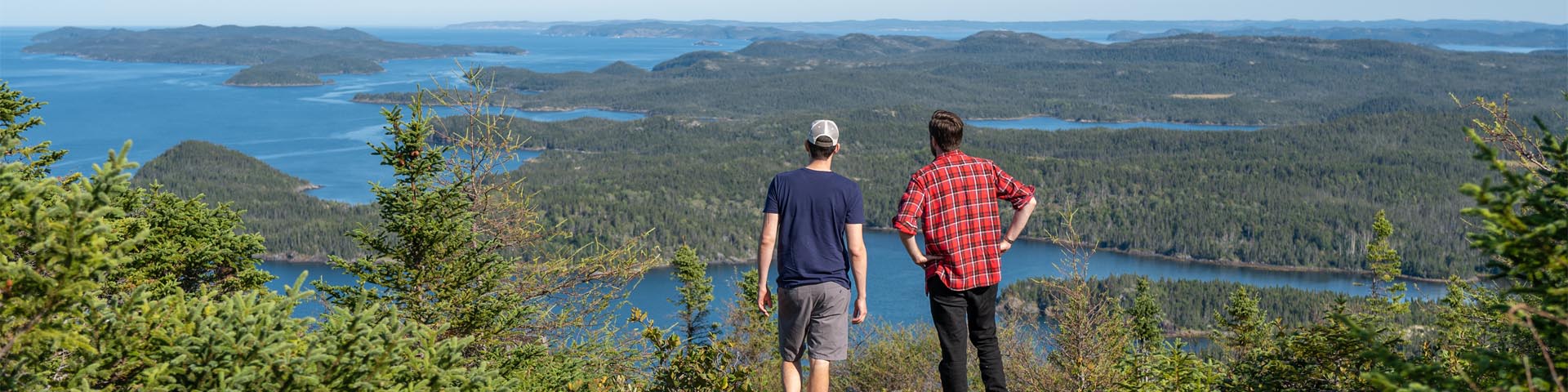 two individuals standing on a coastal cliff, overlooking the ocean