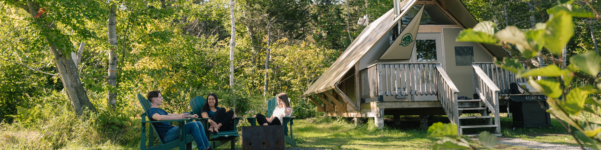 Three people sitting around a campfire next to an oTENTik