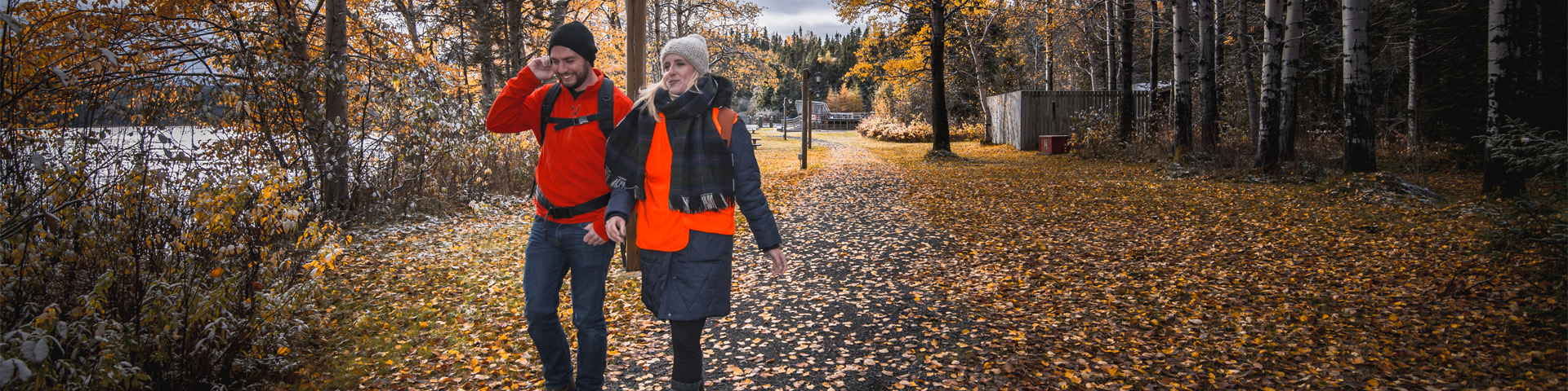 un homme et une femme marchant sur un chemin couvert de feuilles d'automne