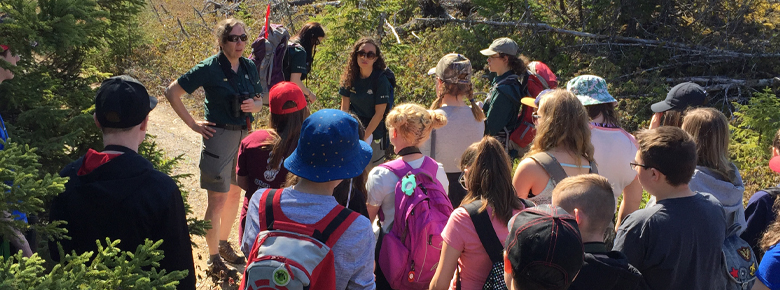 Quatre employés de Parcs Canada emmènent un groupe d'enfants en randonnée.