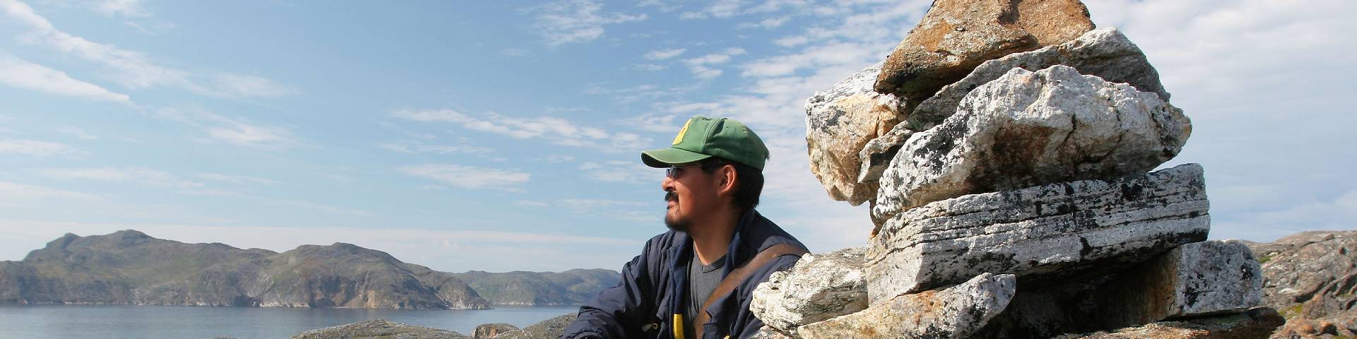 Une personne contemple le terrain à côté d'un tas de pierres à Tongait KakKasuangita SilakKijapvinga-parc national des Monts-Torngat