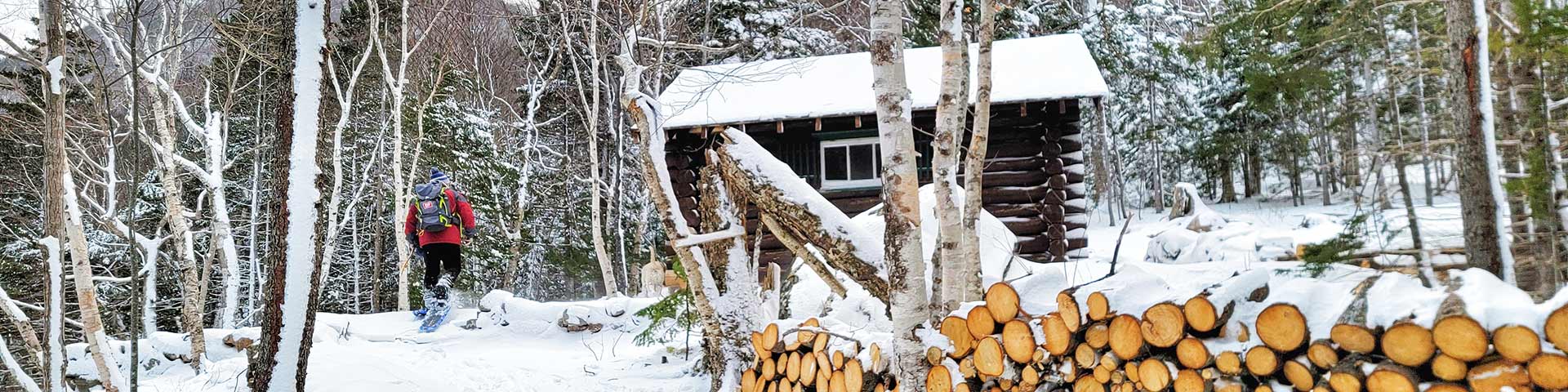 A person snowshoeing to a log cabin