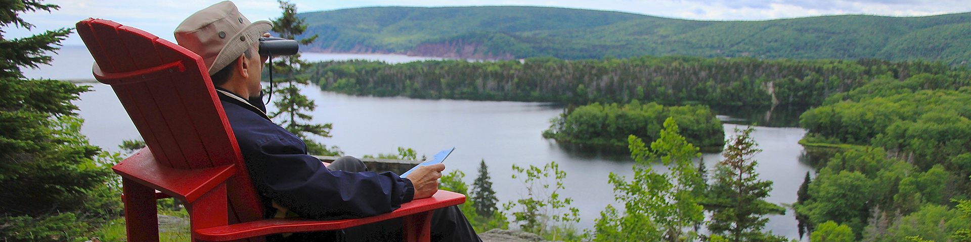 A person sitting in a chair, looking at the landscape through binoculars.