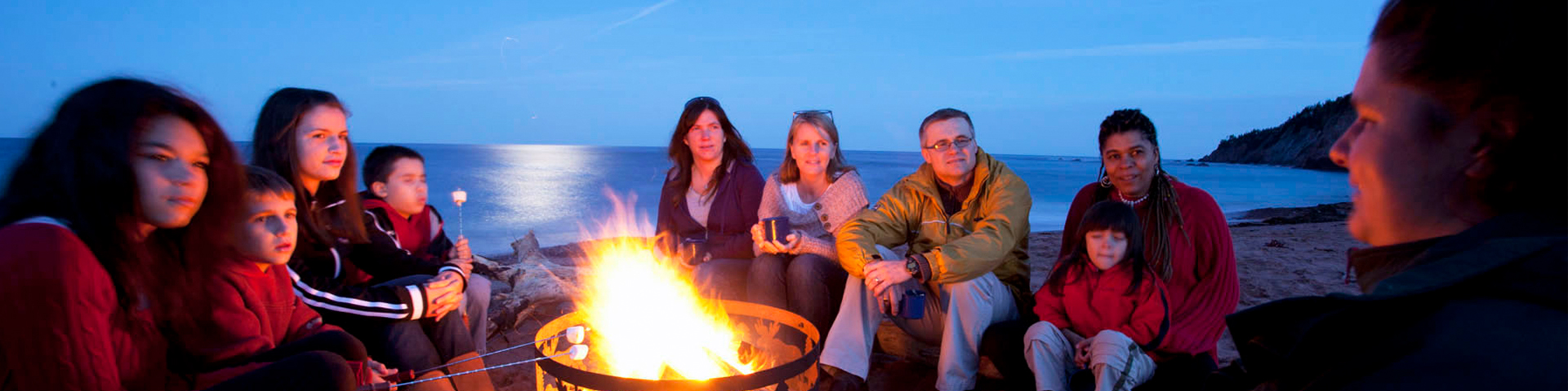 A group of people sitting around a campfire at night.