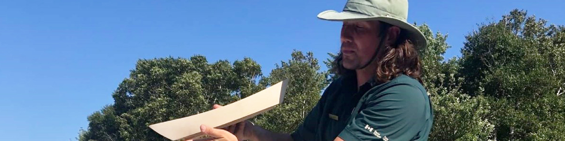 Interprète tenant une petite maquette de doris en bois tout en s’adressant aux visiteurs.