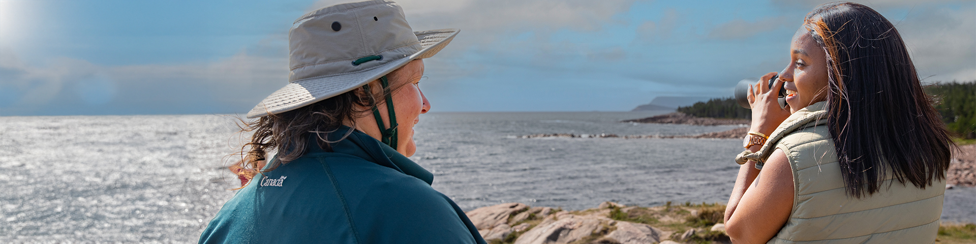 A Parks Canada interpreter looks on as a visitor holds a pair of binoculars.