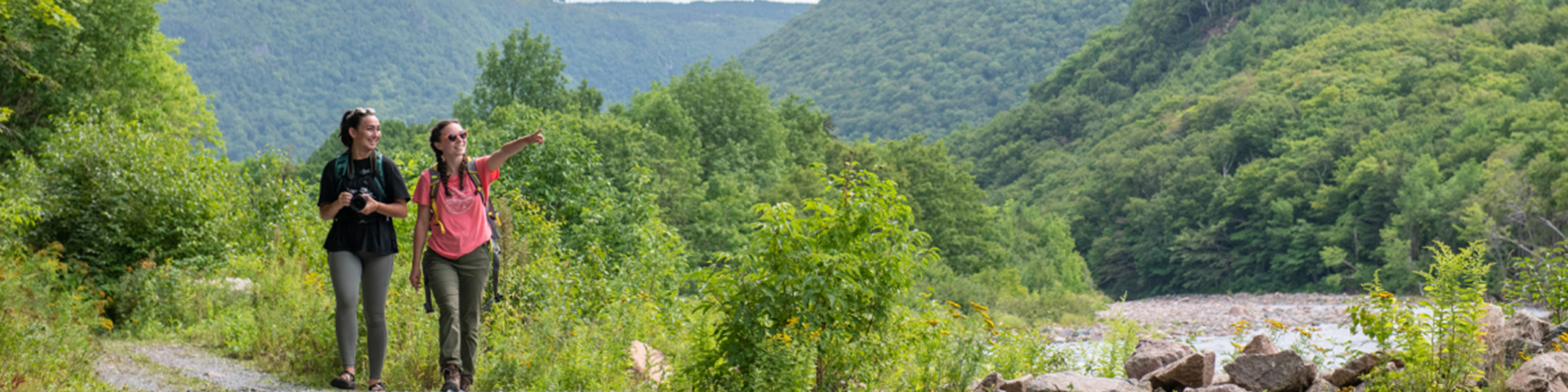 Two visitors stroll along a riverside trail, enjoying the scenery.