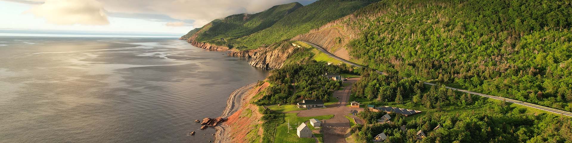 An aerial view of Mkwesaqtuk/Cap-Rouge Campground between the mountains and the sea