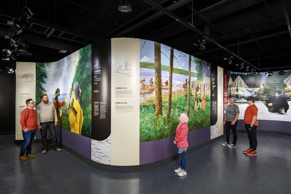 Visitors looking at large floor to ceiling panels of Mi’kmaq art.
