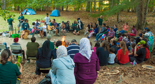 A large group of campers gathered around a campfire.
