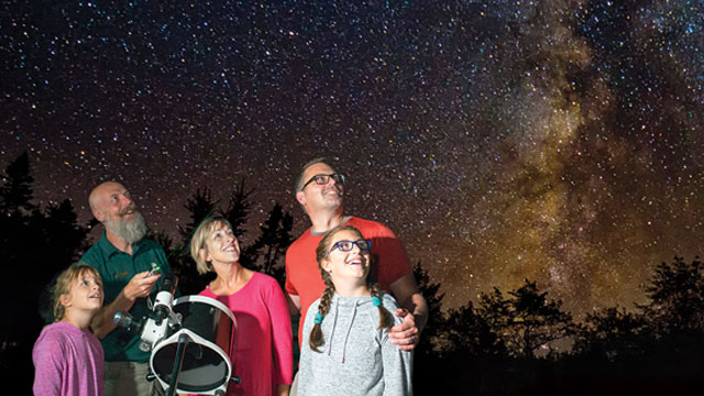 A family star gazing with a large telescope.