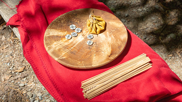 A round wooden game board and game pieces made of wood, bone, and leather.