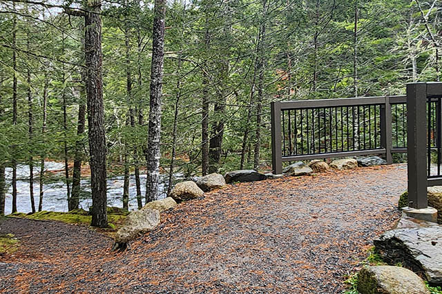 A 24% slope rises from the trail to the pedestrian bridge. This path is lined with large rocks.