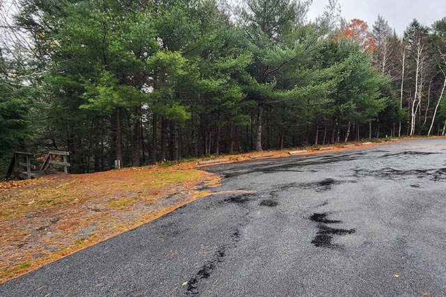 A paved unmarked parking lot with the top of the staircase on the left.