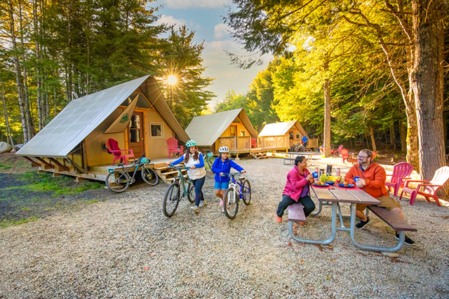 A family in a campsite in the oTENTik village, with bikes and a picnic table.