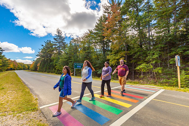 Four people cross the Rainbow Crosswalk.