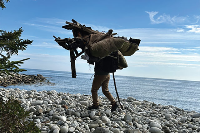 A person carries debris on the beach.