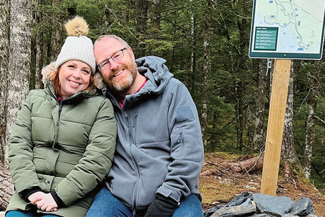 Two people next to a trail sign.
