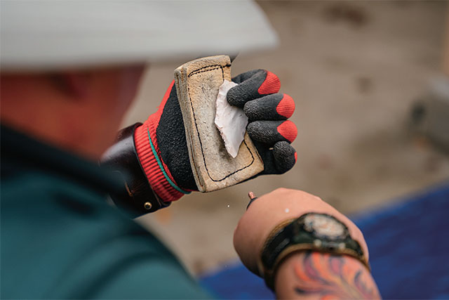 Person holding a piece of flint and a knife.