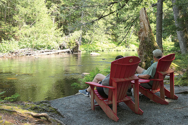 Two people in Parks Canada Red Chairs in the forest.