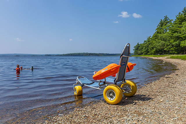 A beach mobility chair next to the water.