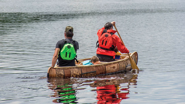 Deux personnes avec des gilets de sauvetage dans un canot.