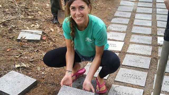Une personne place une pierre sur laquelle est gravé un nom sur un chemin.