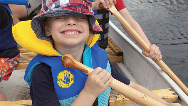 Un enfant avec un grand sourire dans un canoë.
