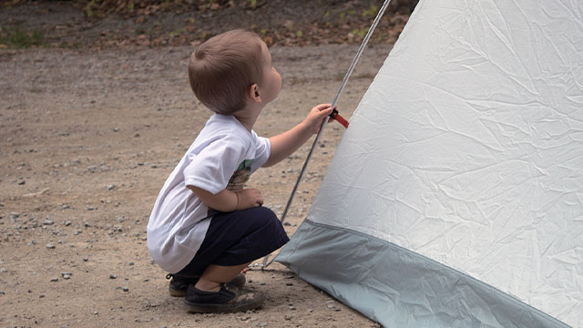 Enfant à côté d'une tente.